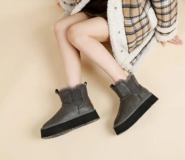 Pair of tan chelsea boots with elastic side panels, chunky platform soles, and soft faux fur lining displayed against a neutral background._17