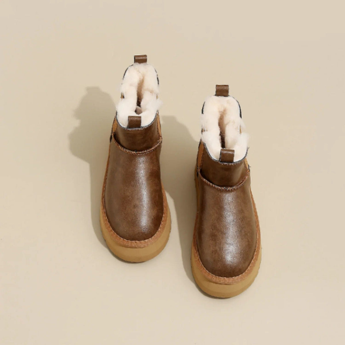 Pair of tan chelsea boots with elastic side panels, chunky platform soles, and soft faux fur lining displayed against a neutral background._2