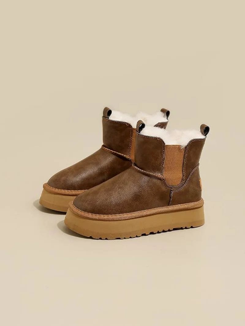 Pair of tan chelsea boots with elastic side panels, chunky platform soles, and soft faux fur lining displayed against a neutral background._6