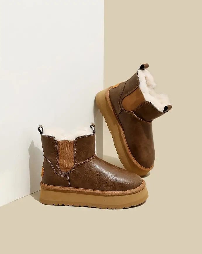 Pair of tan chelsea boots with elastic side panels, chunky platform soles, and soft faux fur lining displayed against a neutral background._7