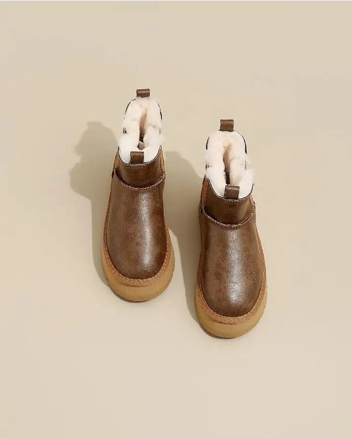 Pair of tan chelsea boots with elastic side panels, chunky platform soles, and soft faux fur lining displayed against a neutral background._8