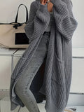 Woman wearing a longline chunky knit cardigan with button front, styled over a layered outfit with a crossbody bag._0