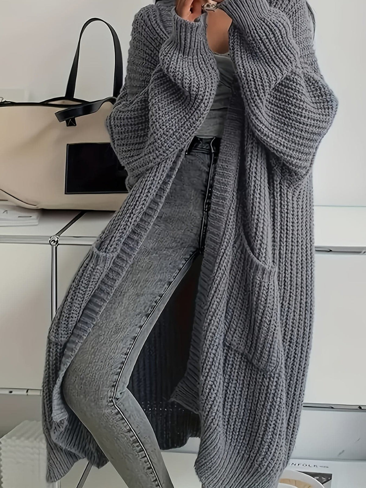 Woman wearing a longline chunky knit cardigan with button front, styled over a layered outfit with a crossbody bag._0