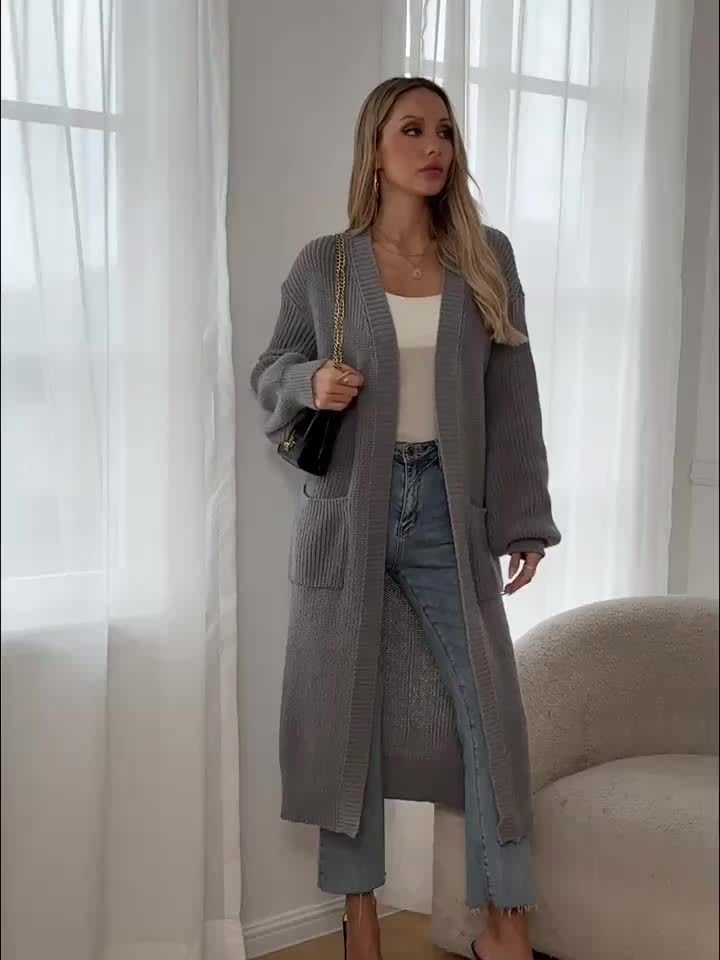 Woman wearing a longline chunky knit cardigan with button front, styled over a layered outfit with a crossbody bag._1