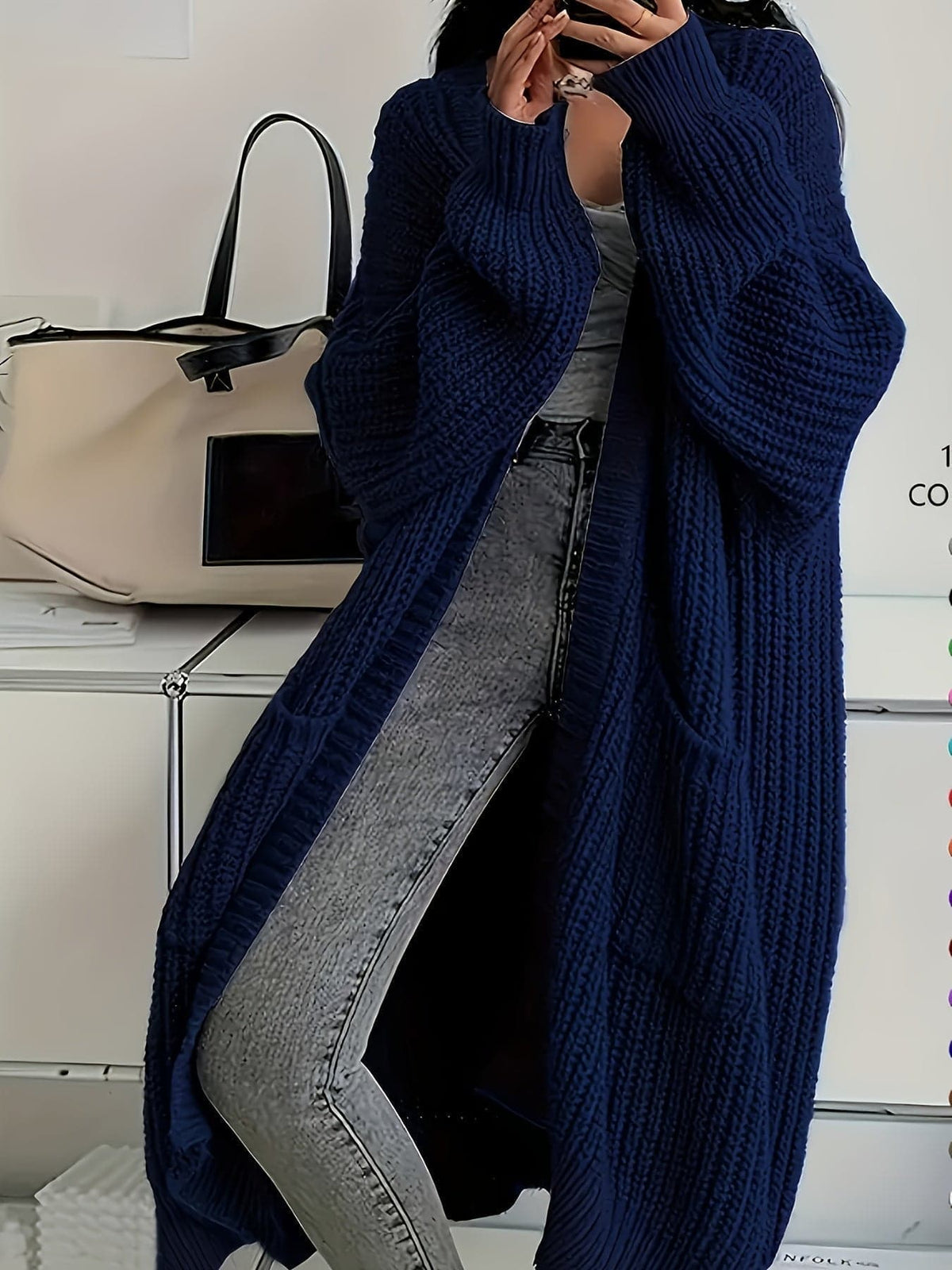 Woman wearing a longline chunky knit cardigan with button front, styled over a layered outfit with a crossbody bag._7