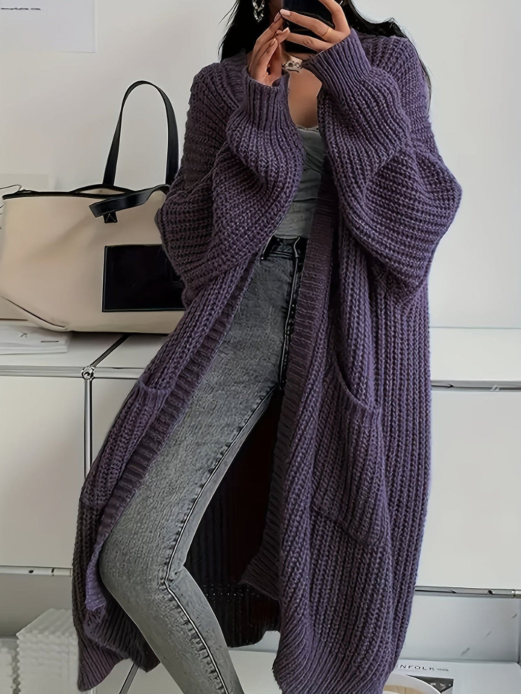 Woman wearing a longline chunky knit cardigan with button front, styled over a layered outfit with a crossbody bag._9