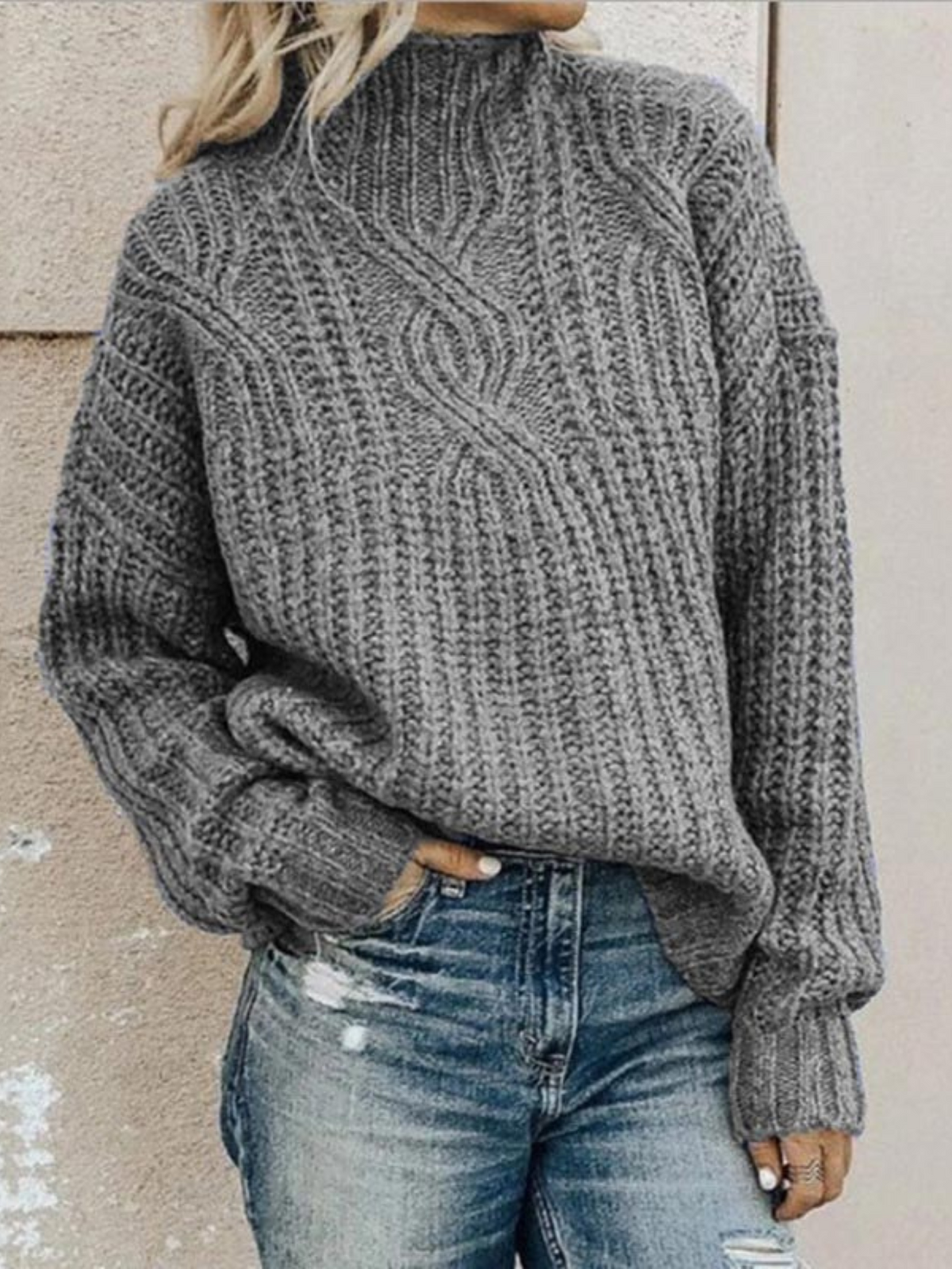 Gray chunky knit mock neck sweater with pronounced textured stitching, long sleeves, and a relaxed silhouette paired with denim.