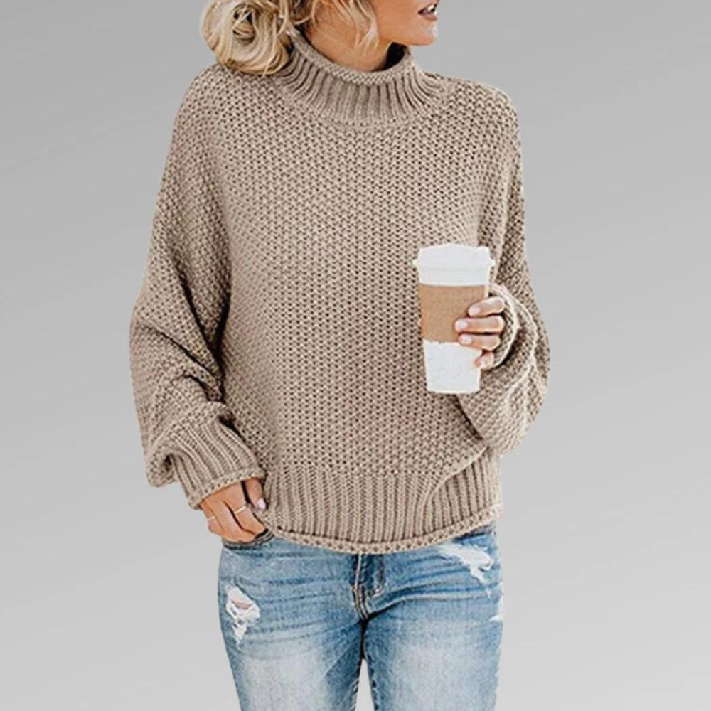 Taupe chunky knit turtleneck sweater with a relaxed fit, ribbed cuffs and hem, styled with distressed jeans and a takeaway coffee.
