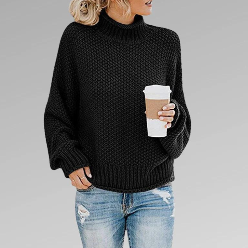 Black chunky knit turtleneck sweater with ribbed neckline, cuffs, and hem, shown with distressed blue jeans.