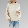 Woman wearing a chunky knit oversized turtleneck sweater in cream paired with distressed blue jeans while holding a coffee cup._0