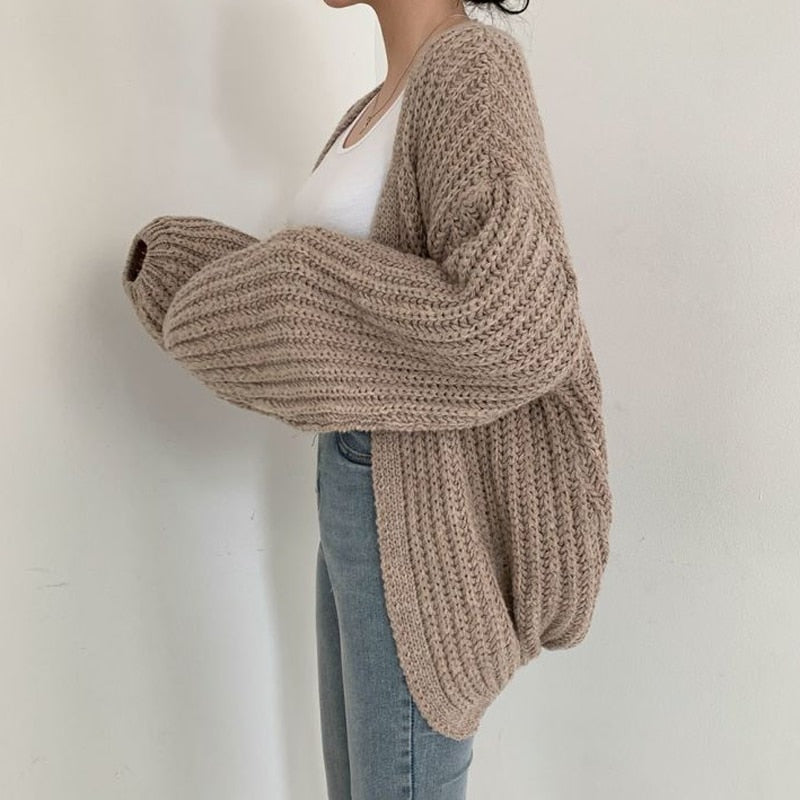 Side view of the taupe open-front cardigan showing its relaxed drape, extended back, and voluminous balloon sleeve.