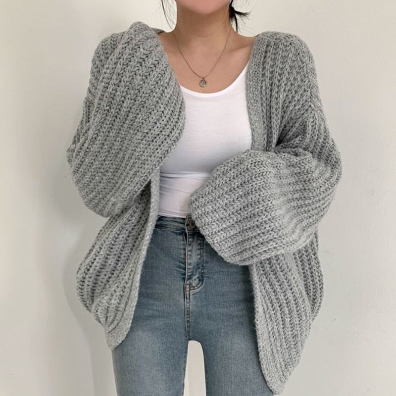 Gray chunky open-front cardigan styled with a white top and jeans, featuring oversized sleeves and a softly curved hem.