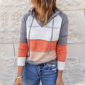Woman wearing a grey, white, coral and blush striped hooded knit sweater with pointelle detail and drawstrings, paired with blue jeans._0