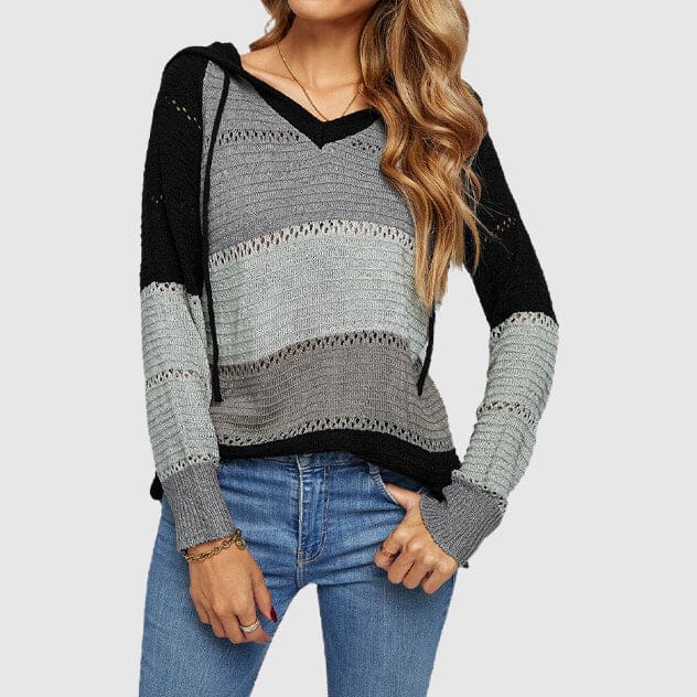 Woman wearing a grey, white, coral and blush striped hooded knit sweater with pointelle detail and drawstrings, paired with blue jeans._4