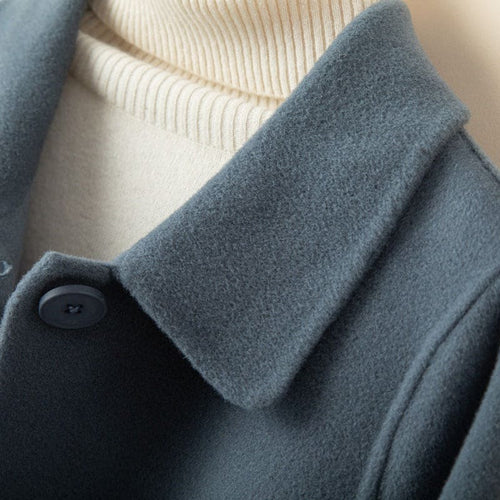 A mid length button front coat with a pointed collar, long sleeves, and side welt pockets shown on a hanger._5
