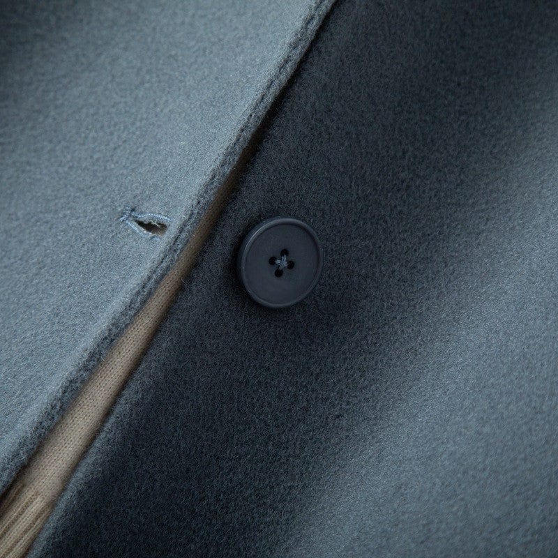 A mid length button front coat with a pointed collar, long sleeves, and side welt pockets shown on a hanger._6