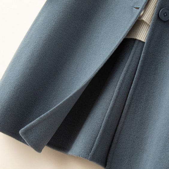 A mid length button front coat with a pointed collar, long sleeves, and side welt pockets shown on a hanger._7
