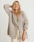 Woman wearing an oversized ribbed cardigan with button-front closure and relaxed cocoon fit, styled with neutral pants._0
