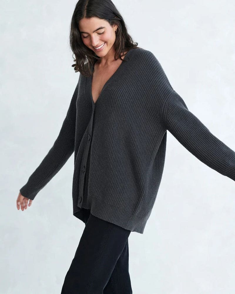 Woman wearing an oversized ribbed cardigan with button-front closure and relaxed cocoon fit, styled with neutral pants._11