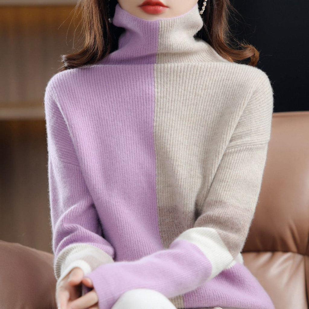 Woman wearing a color block turtleneck sweater with geometric panels in blue and beige tones, paired with black pants and a belt._5