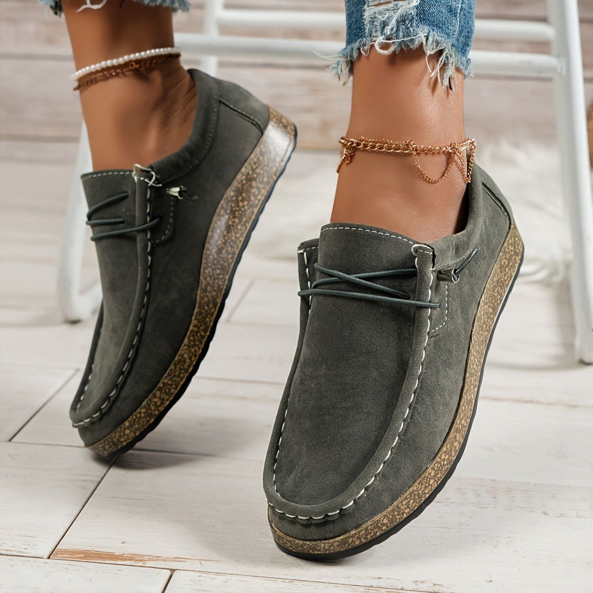 Woman wearing platform loafers with lace-up detail, cork-effect sole, and distressed denim shorts with chain anklet._0