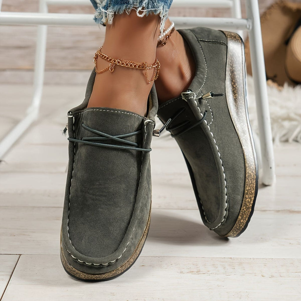 Woman wearing platform loafers with lace-up detail, cork-effect sole, and distressed denim shorts with chain anklet._2