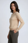 Side view of a beige crew neck sweater with long sleeves, ribbed cuffs and hem, styled with gray trousers.
