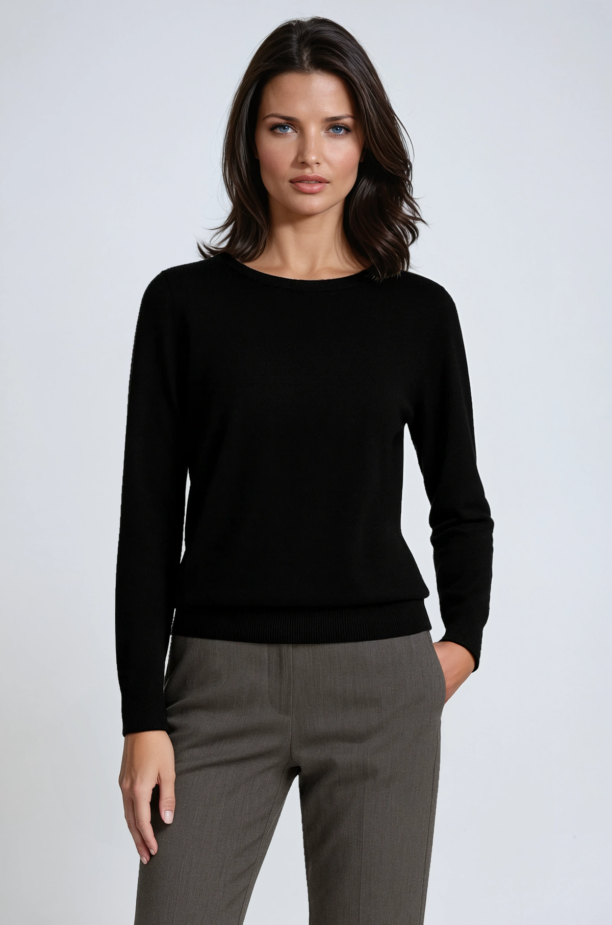 Black crew neck sweater with long sleeves and a ribbed hem, shown with one hand in a trouser pocket.