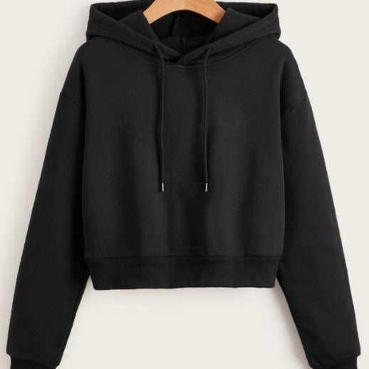 Black cropped pullover hoodie with a roomy hood, long sleeves, ribbed hem, and hanging drawstrings on a wooden hanger.