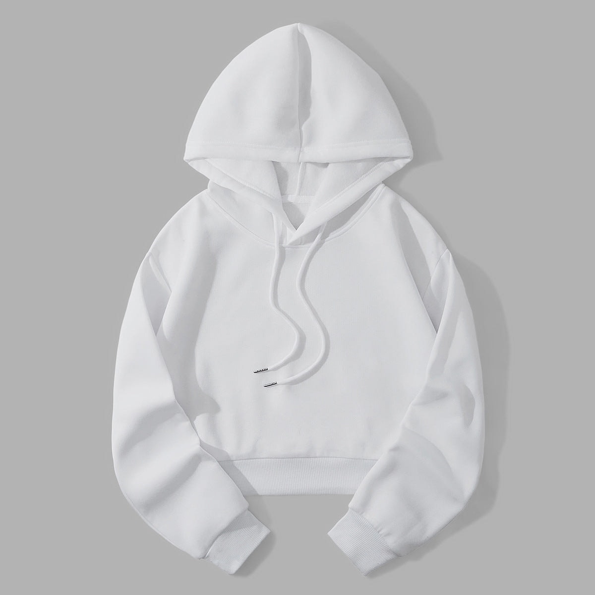 White cropped hoodie laid flat against a gray background, featuring a raised hood, long sleeves, ribbed cuffs, and front drawstrings.