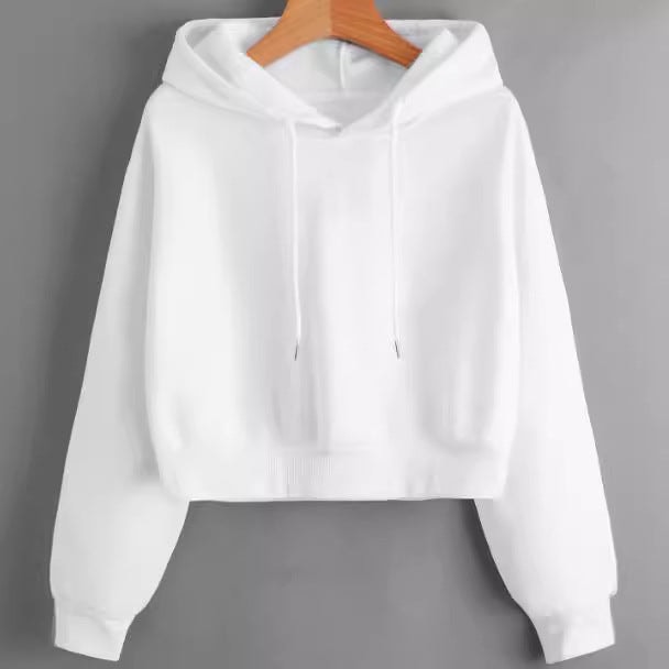 White cropped hoodie displayed on a hanger, showing its pullover front, roomy sleeves, ribbed cuffs, and adjustable hood drawstrings.