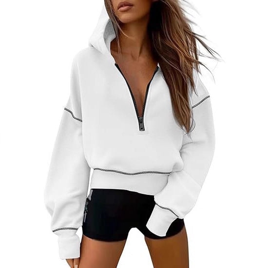 White cropped half-zip hoodie with black contrast stitching, hood, and long sleeves styled with black shorts.