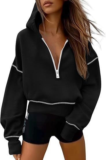 Black cropped hoodie shown with the hood raised, white half-zip, and white contrast stitching outlining the sleeves and hem.