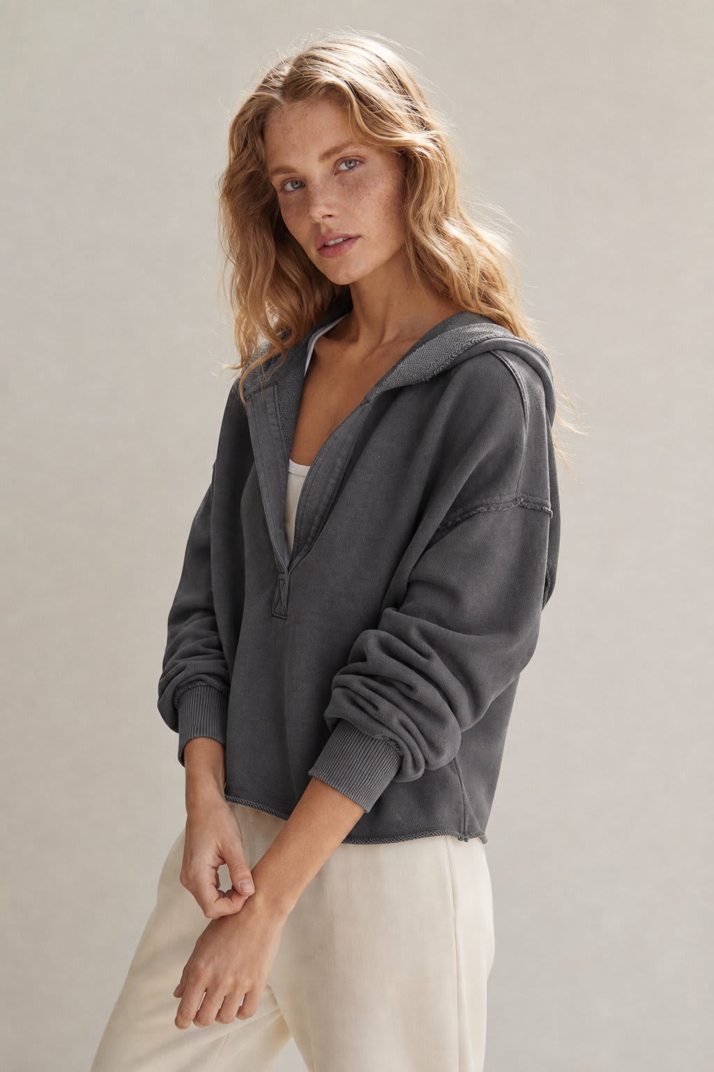 Woman wearing a relaxed cropped hoodie with collared neckline and long sleeves in a neutral indoor setting_1