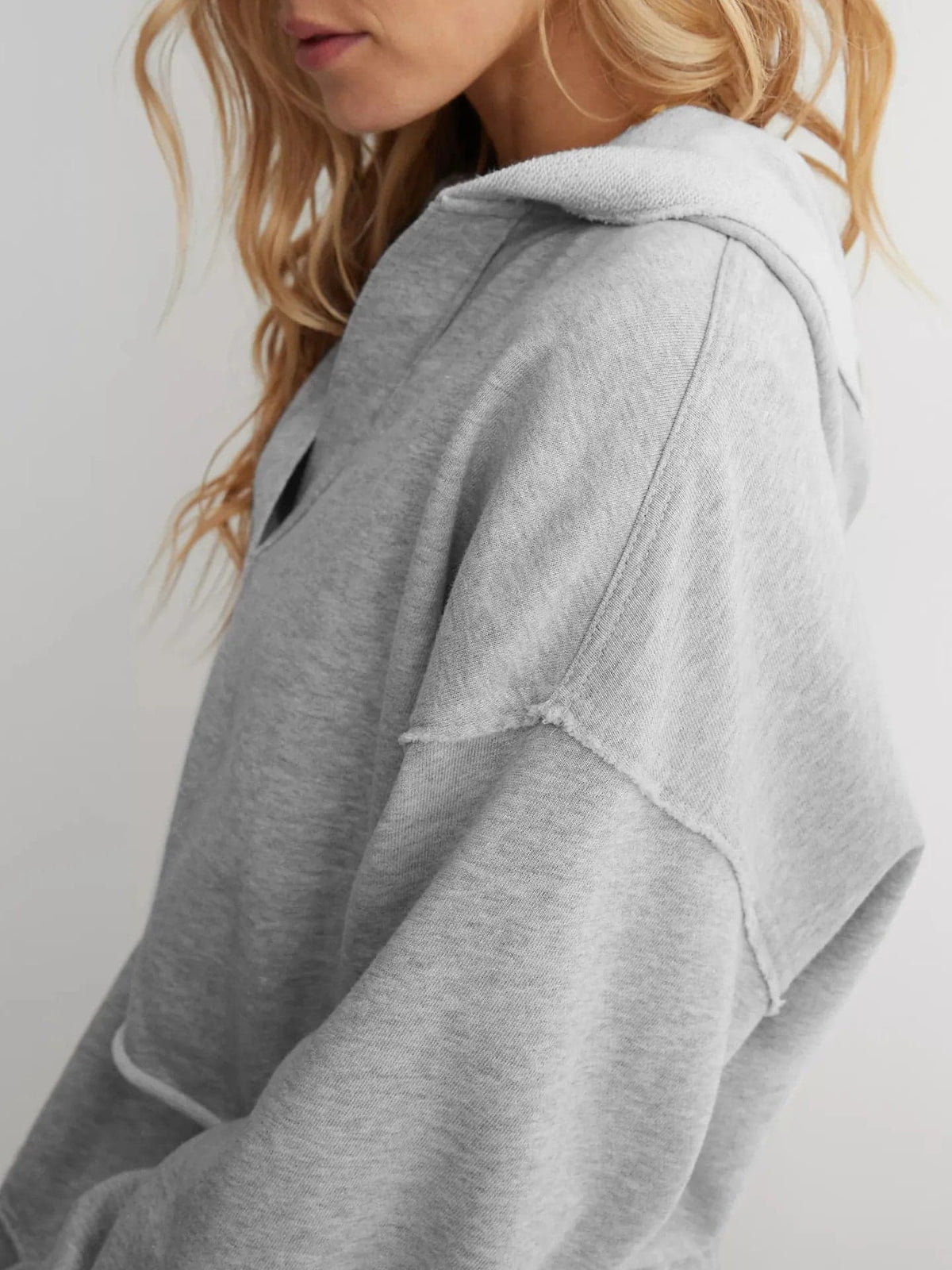 Woman wearing a relaxed cropped hoodie with collared neckline and long sleeves in a neutral indoor setting_24