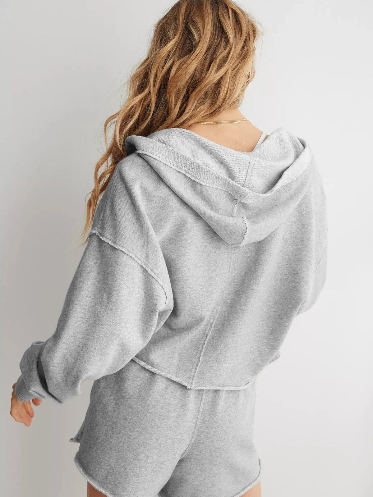 Woman wearing a relaxed cropped hoodie with collared neckline and long sleeves in a neutral indoor setting_25