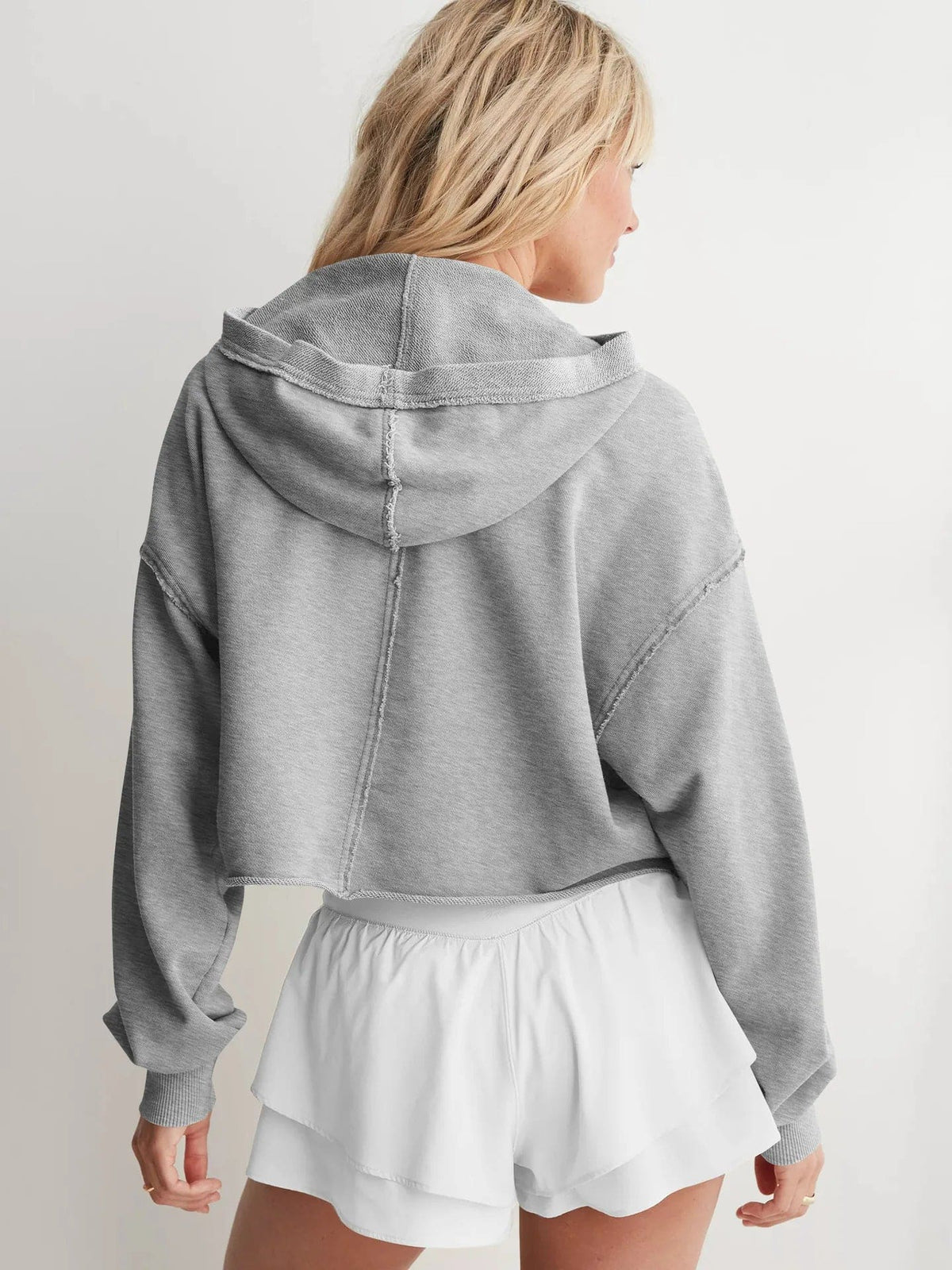 Woman wearing a relaxed cropped hoodie with collared neckline and long sleeves in a neutral indoor setting_26