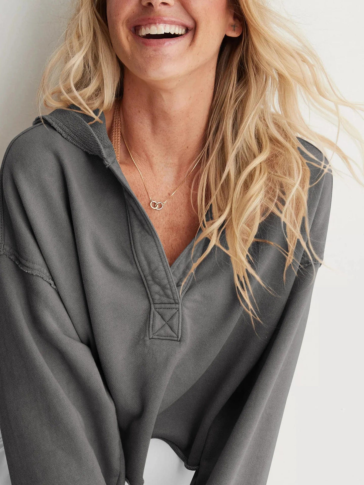 Woman wearing a relaxed cropped hoodie with collared neckline and long sleeves in a neutral indoor setting_30