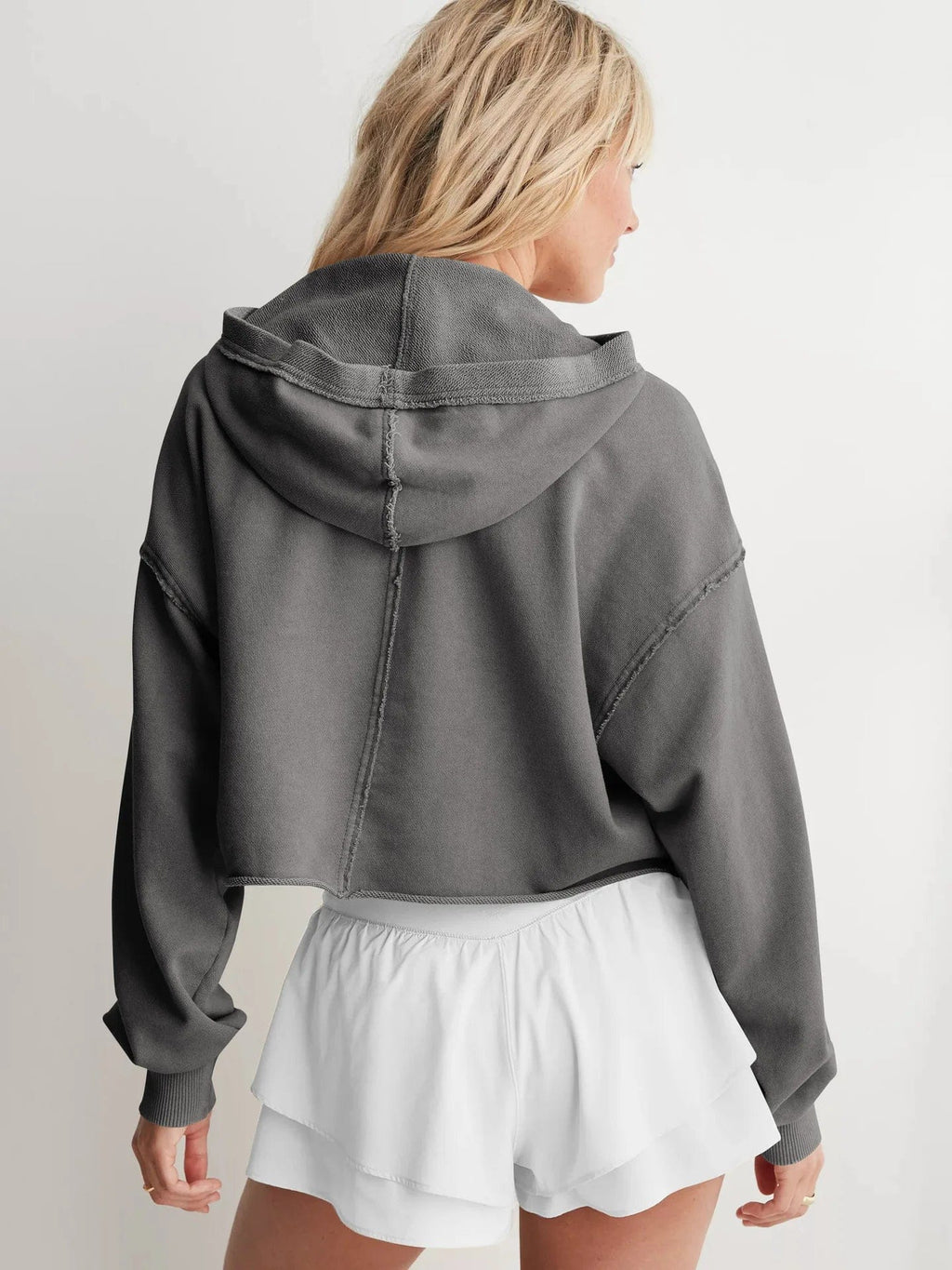Woman wearing a relaxed cropped hoodie with collared neckline and long sleeves in a neutral indoor setting_32