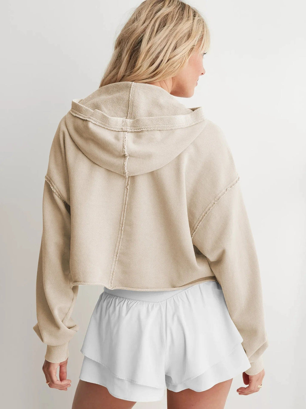 Woman wearing a relaxed cropped hoodie with collared neckline and long sleeves in a neutral indoor setting_36