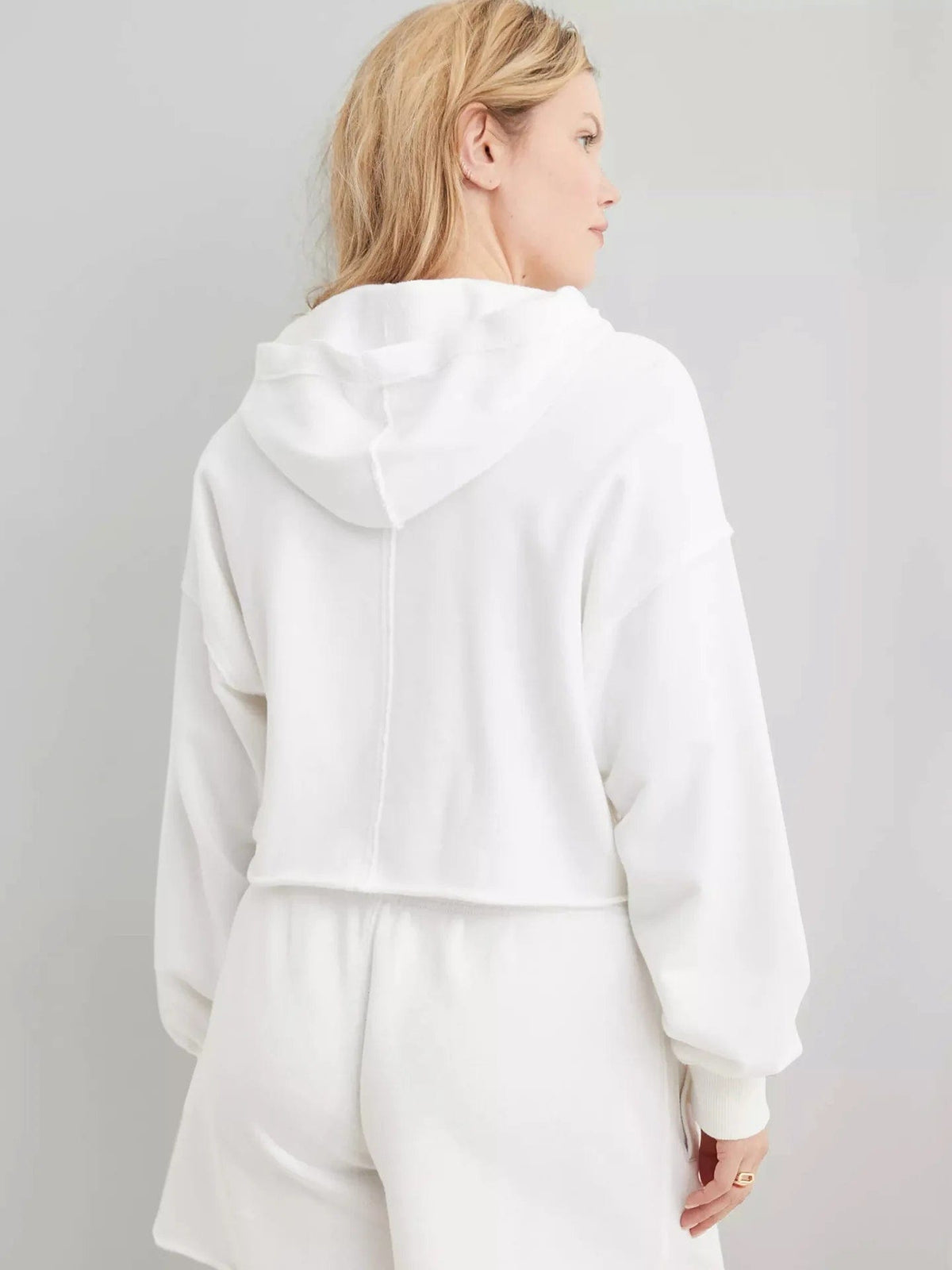 Woman wearing a relaxed cropped hoodie with collared neckline and long sleeves in a neutral indoor setting_42