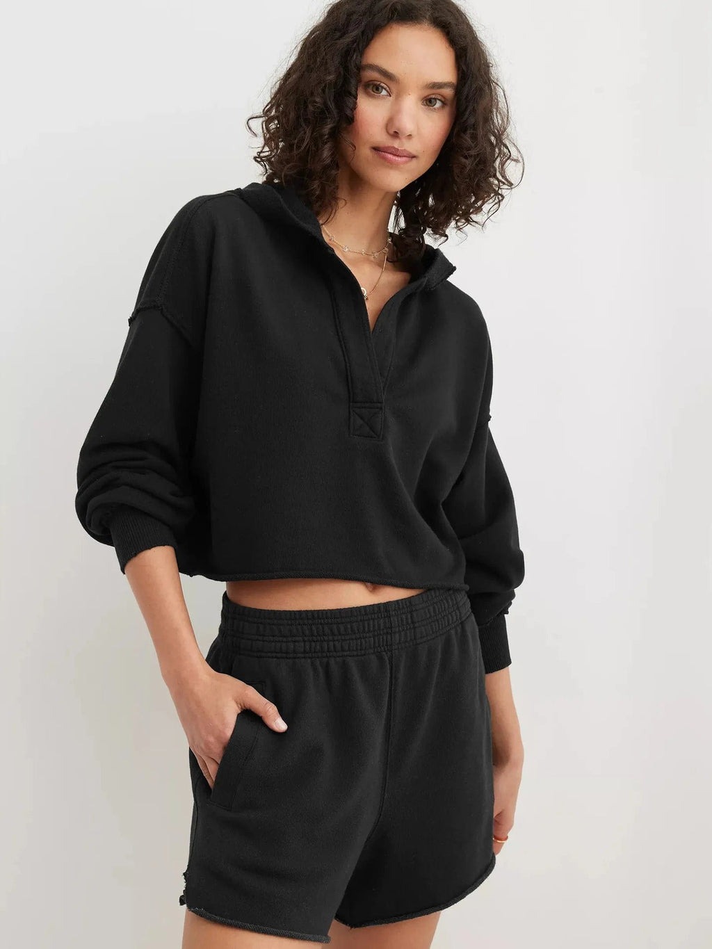 Woman wearing a relaxed cropped hoodie with collared neckline and long sleeves in a neutral indoor setting_47