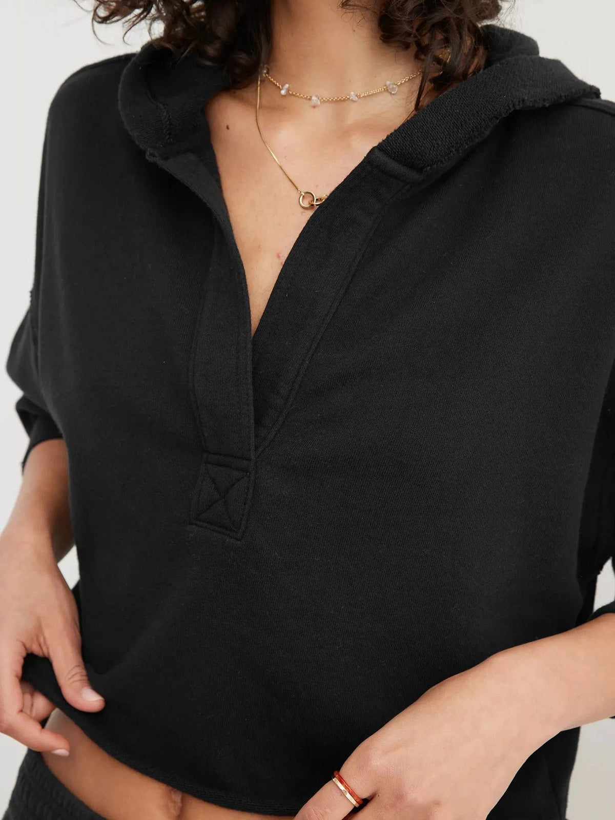 Woman wearing a relaxed cropped hoodie with collared neckline and long sleeves in a neutral indoor setting_49