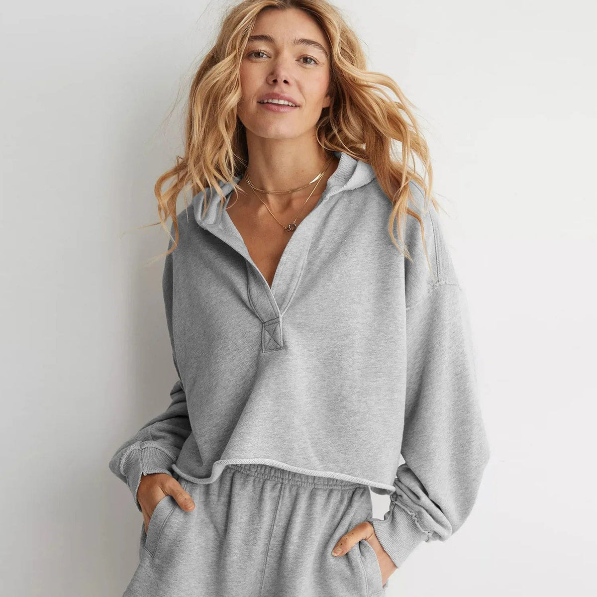 Woman wearing a relaxed cropped hoodie with collared neckline and long sleeves in a neutral indoor setting_8