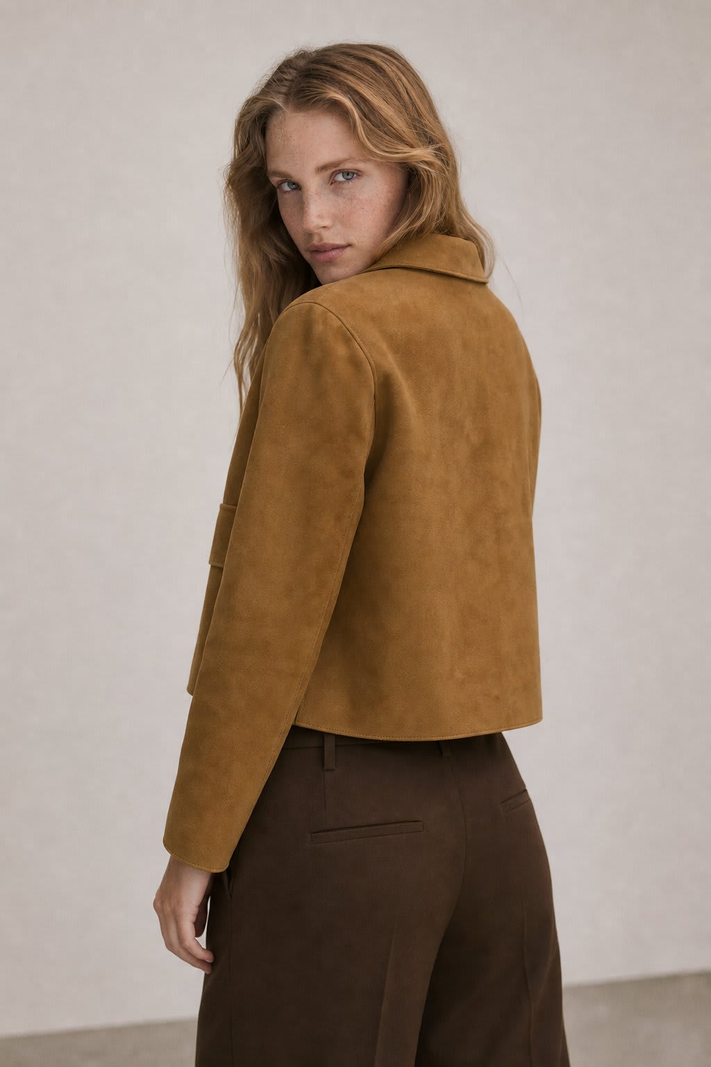 Woman wearing a cropped jacket with collared neckline, button front closure, and flap pockets over a black outfit._2