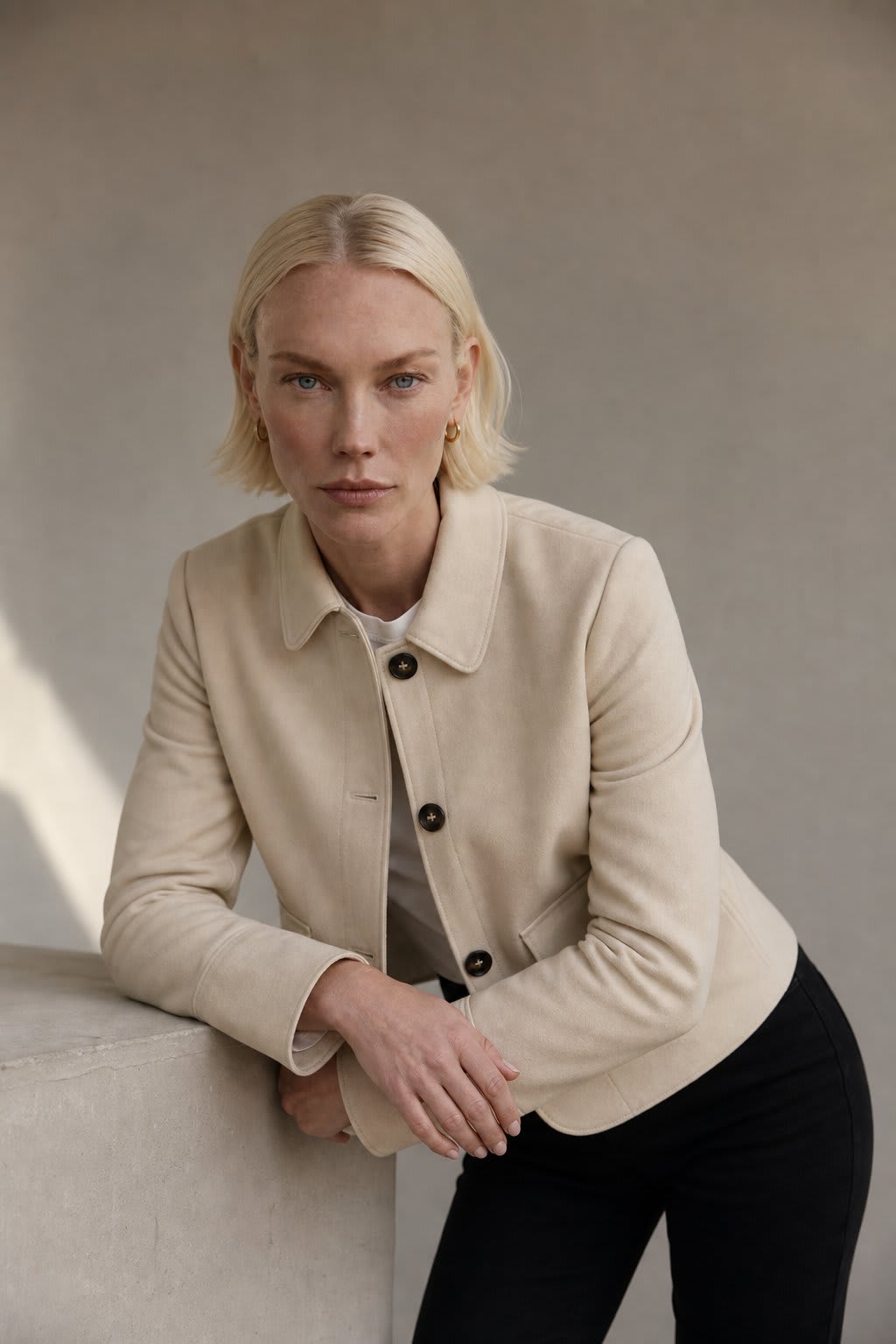 Woman wearing a cropped jacket with collared neckline, button front closure, and flap pockets over a black outfit._4