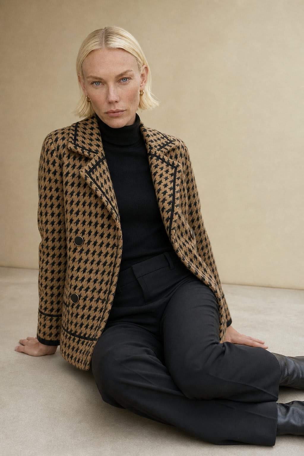 Woman wearing a cropped houndstooth knit jacket with double-breasted buttons over a black turtleneck._1