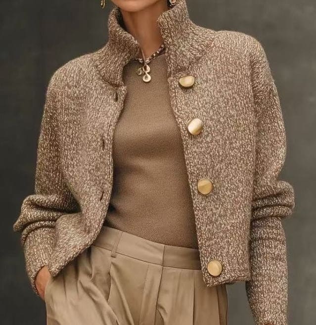 Woman wearing a cropped tailored jacket with oversized gold buttons, styled with a fitted turtleneck and pleated trousers in neutral tones._2