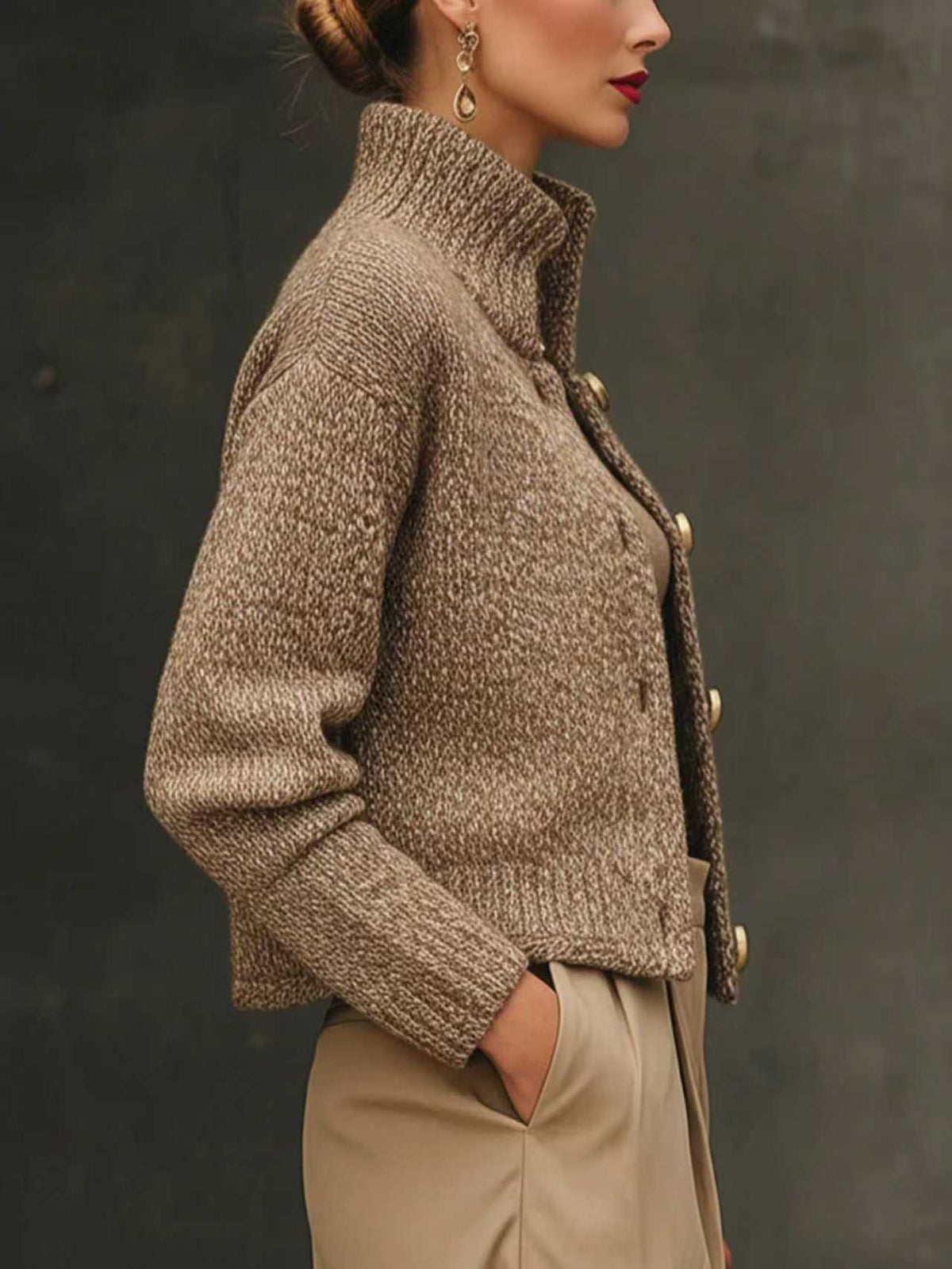 Woman wearing a cropped tailored jacket with oversized gold buttons, styled with a fitted turtleneck and pleated trousers in neutral tones._3