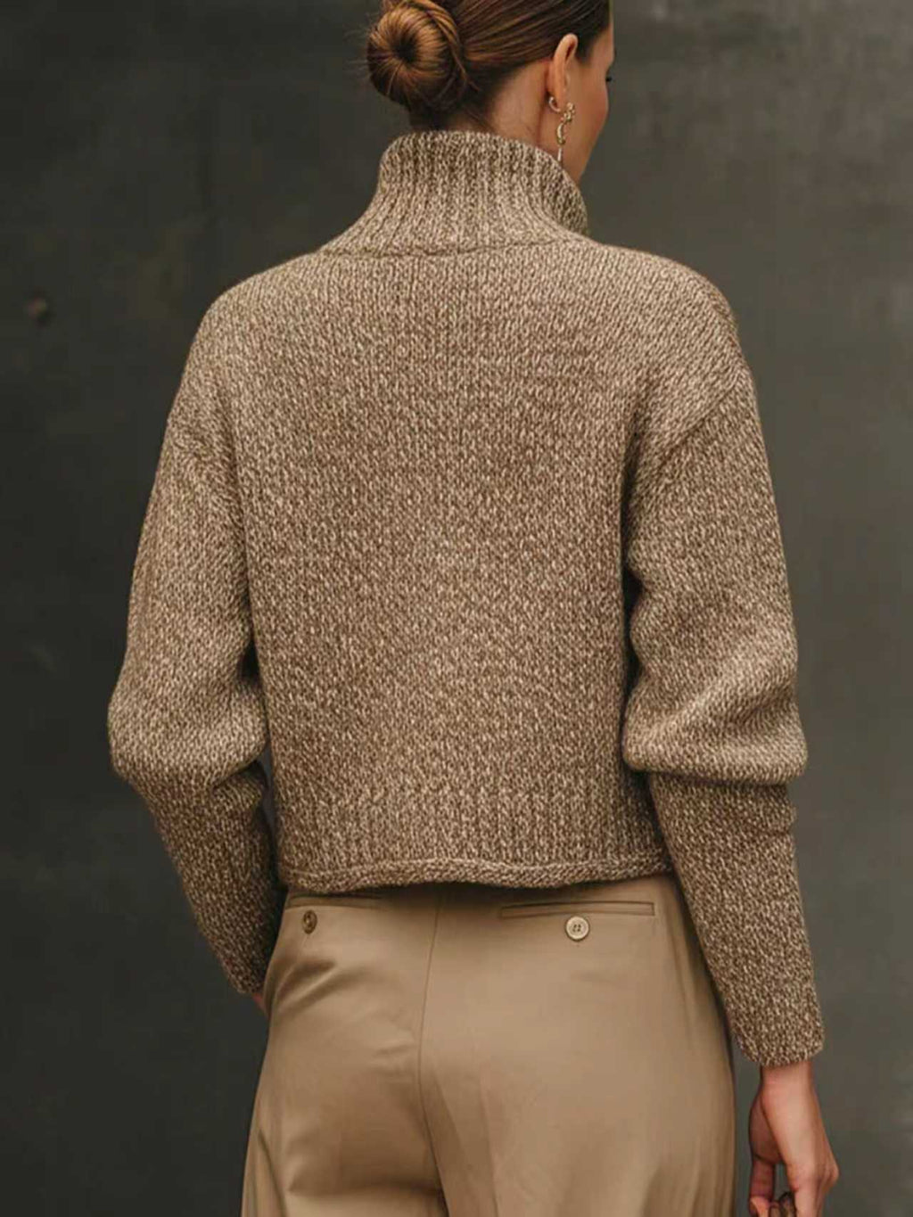 Woman wearing a cropped tailored jacket with oversized gold buttons, styled with a fitted turtleneck and pleated trousers in neutral tones._4
